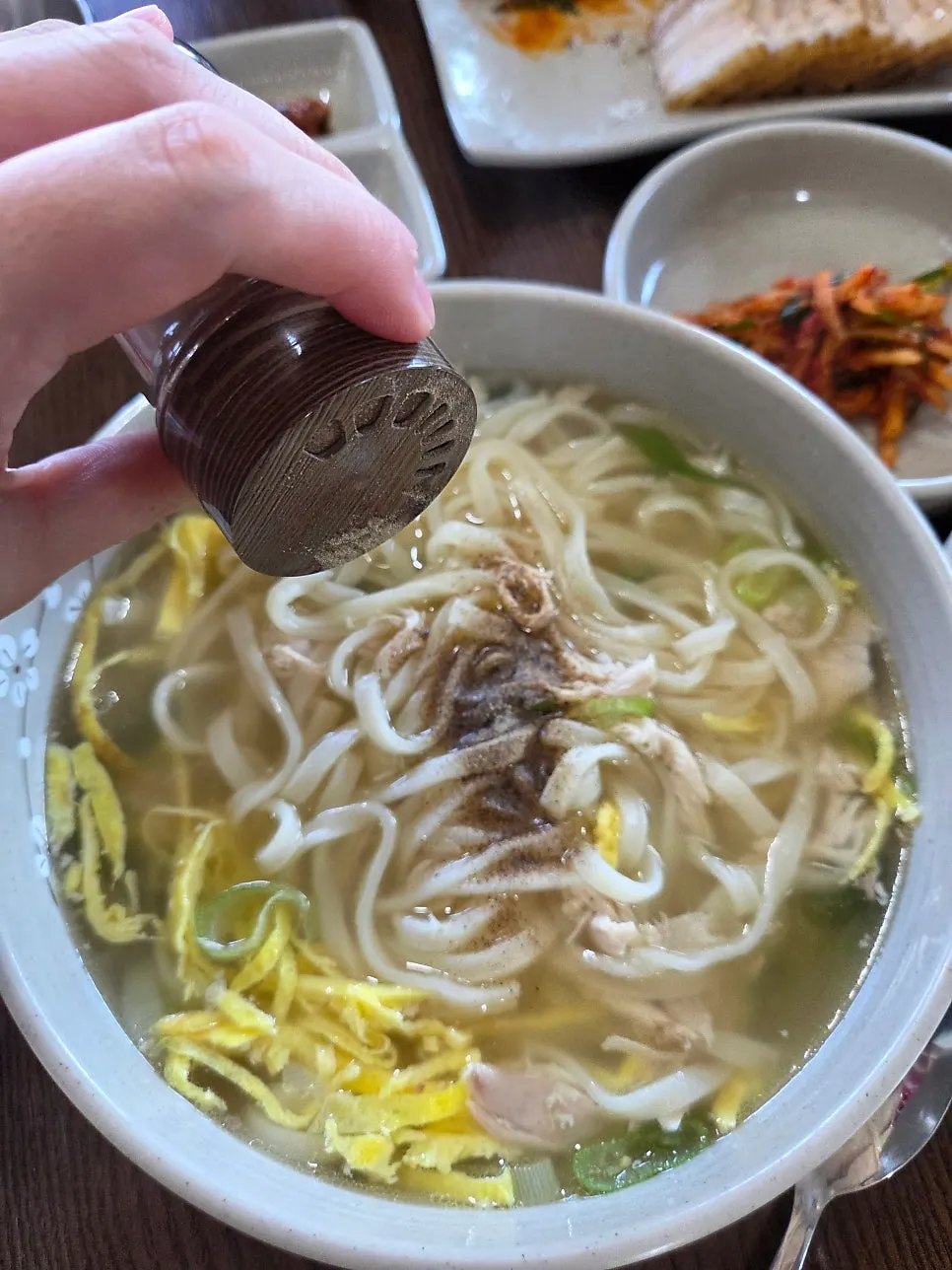 Bowl of chicken kalguksu sprinkled with pepper