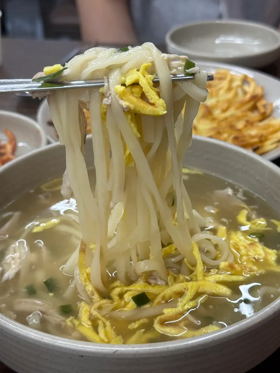 Noodles from the chicken kalguksu lifted out with chopsticks