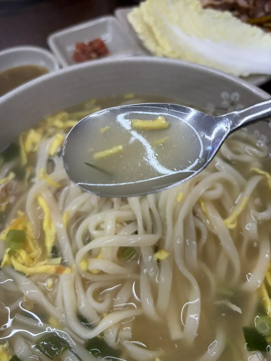 A bowl of chicken kalguksu with a light chicken-based broth