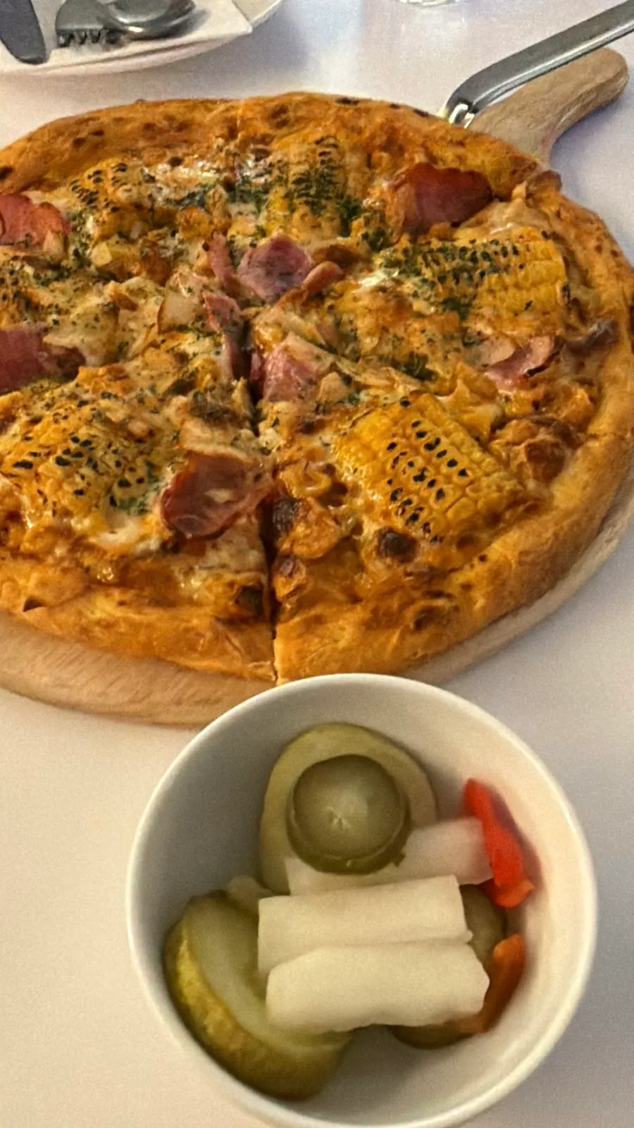 Corn pizza topped with a whole ear of corn