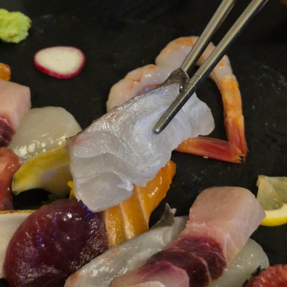 A single piece of sashimi held with chopsticks