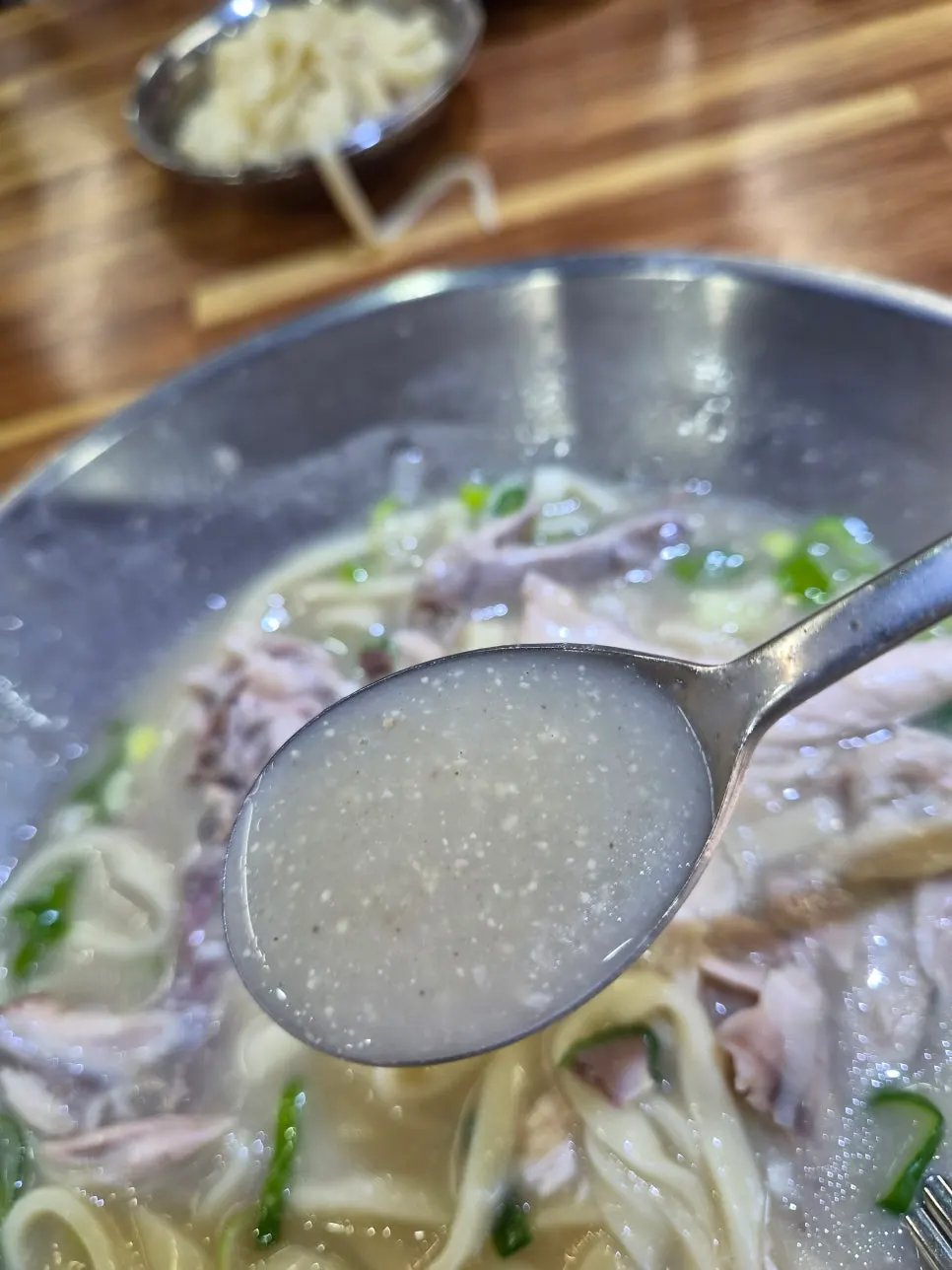 Close-up of the milky dak sagol broth in the dak kalguksu