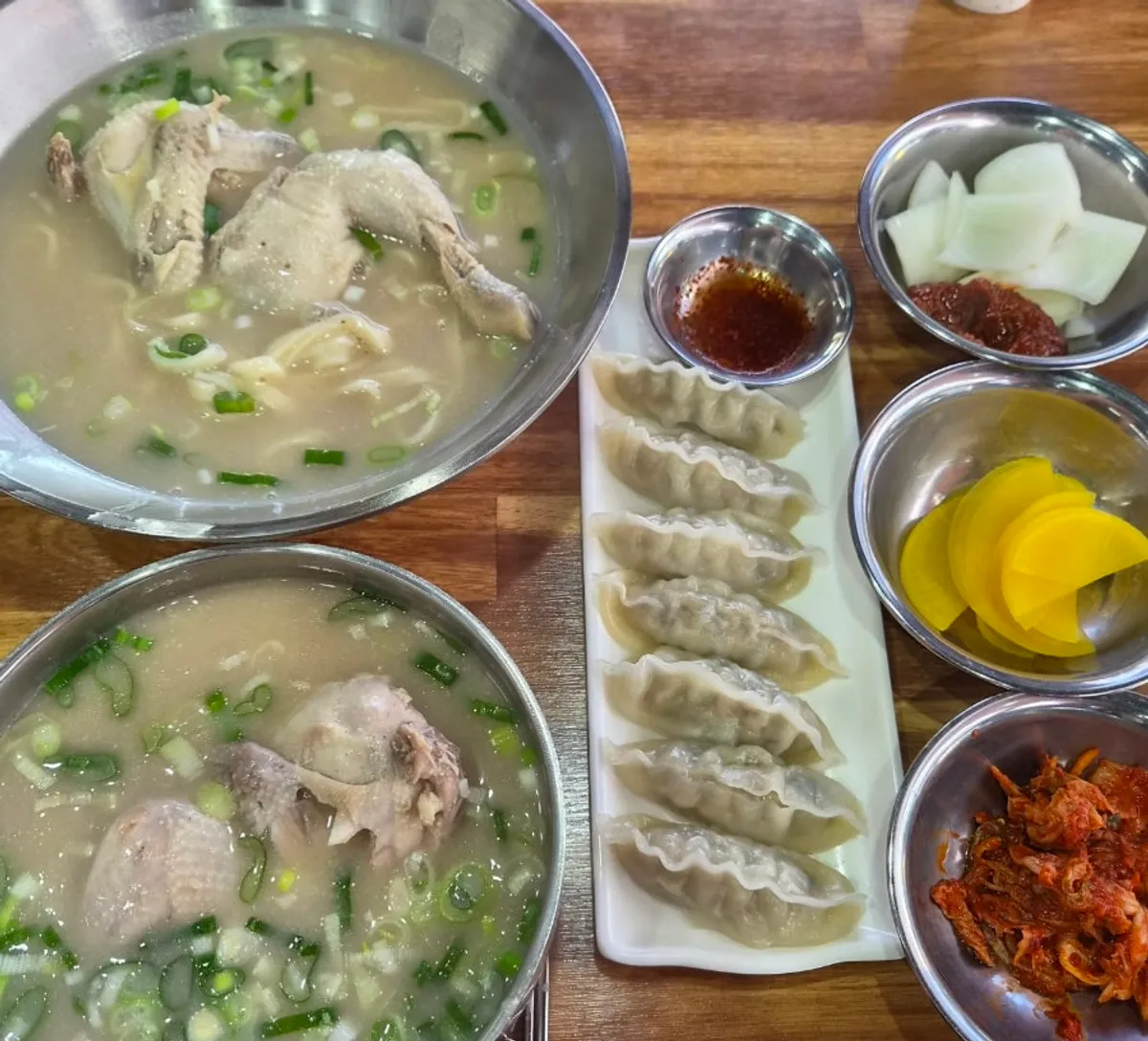 Two bowls of dak-kalguksu and dak-gomtang each with half a chicken