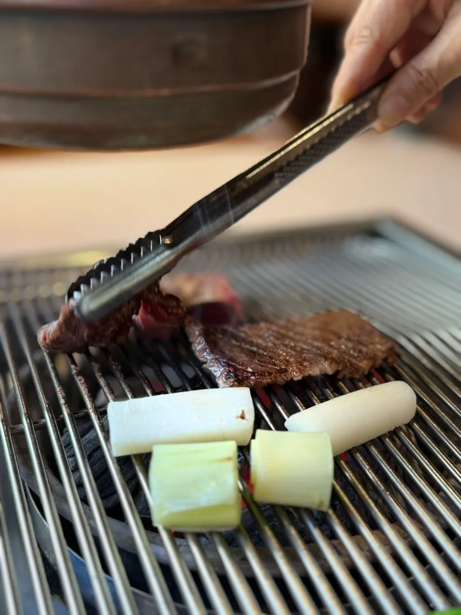 Hanwoo raw short ribs grilling with peppers and green onion