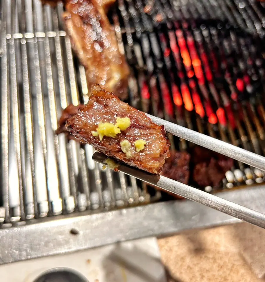 Charcoal-marinated beef ribs grilled by a staff member