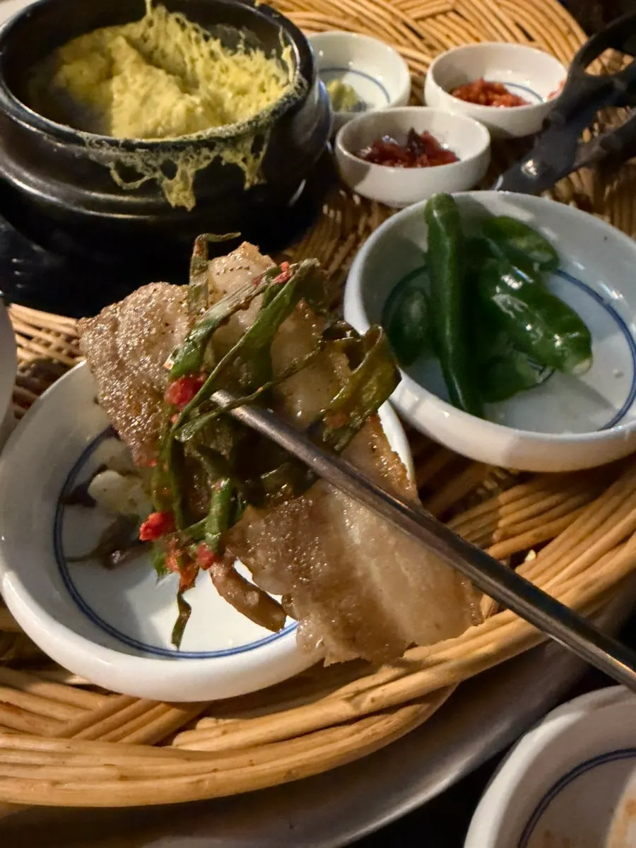 A piece of pork belly wrapped in green onion kimchi