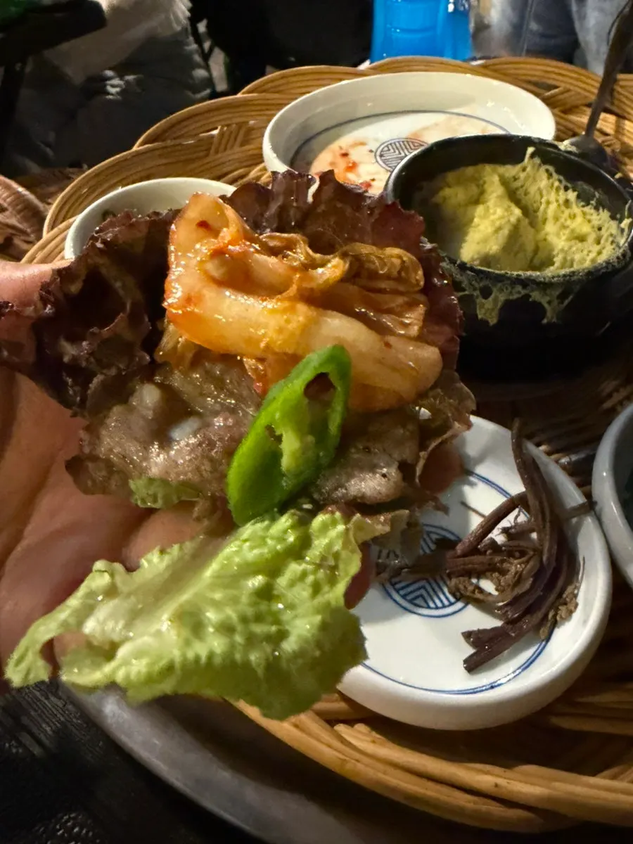 A lettuce wrap with meat and side dishes