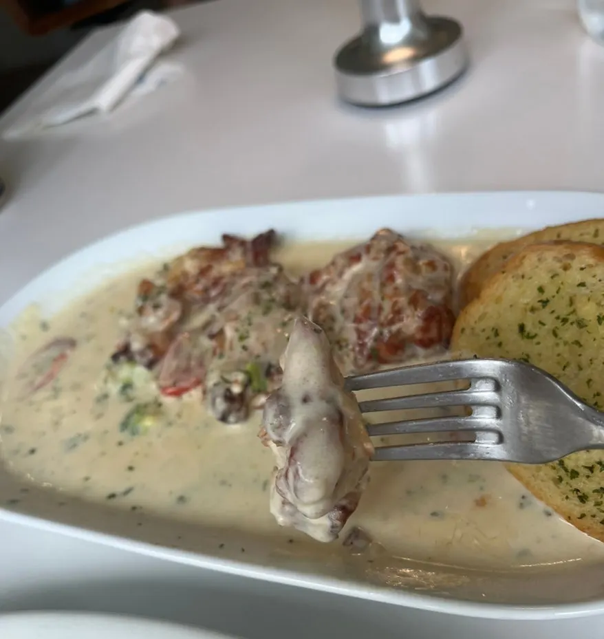 A bite of chicken steak topped with cream sauce
