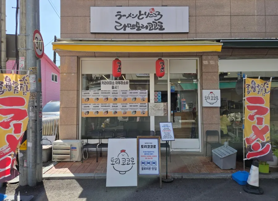 Exterior of Torikokoro Byeollae with yellow awning and flags
