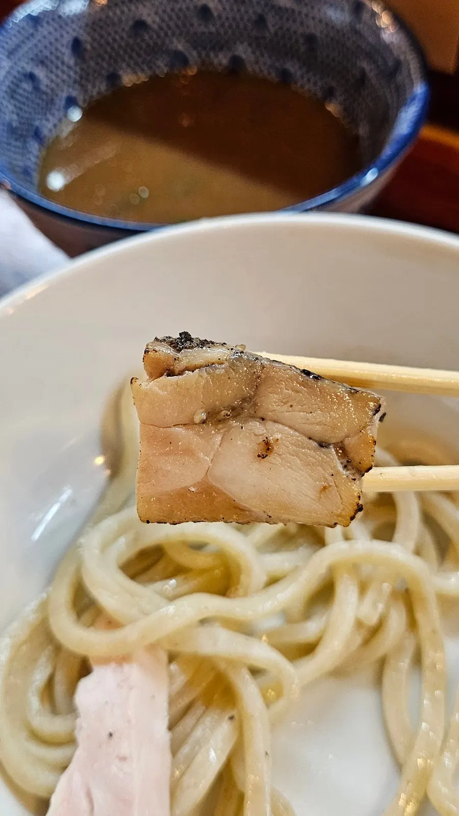 Noodles dipped two-thirds of the way into the tsukemen sauce
