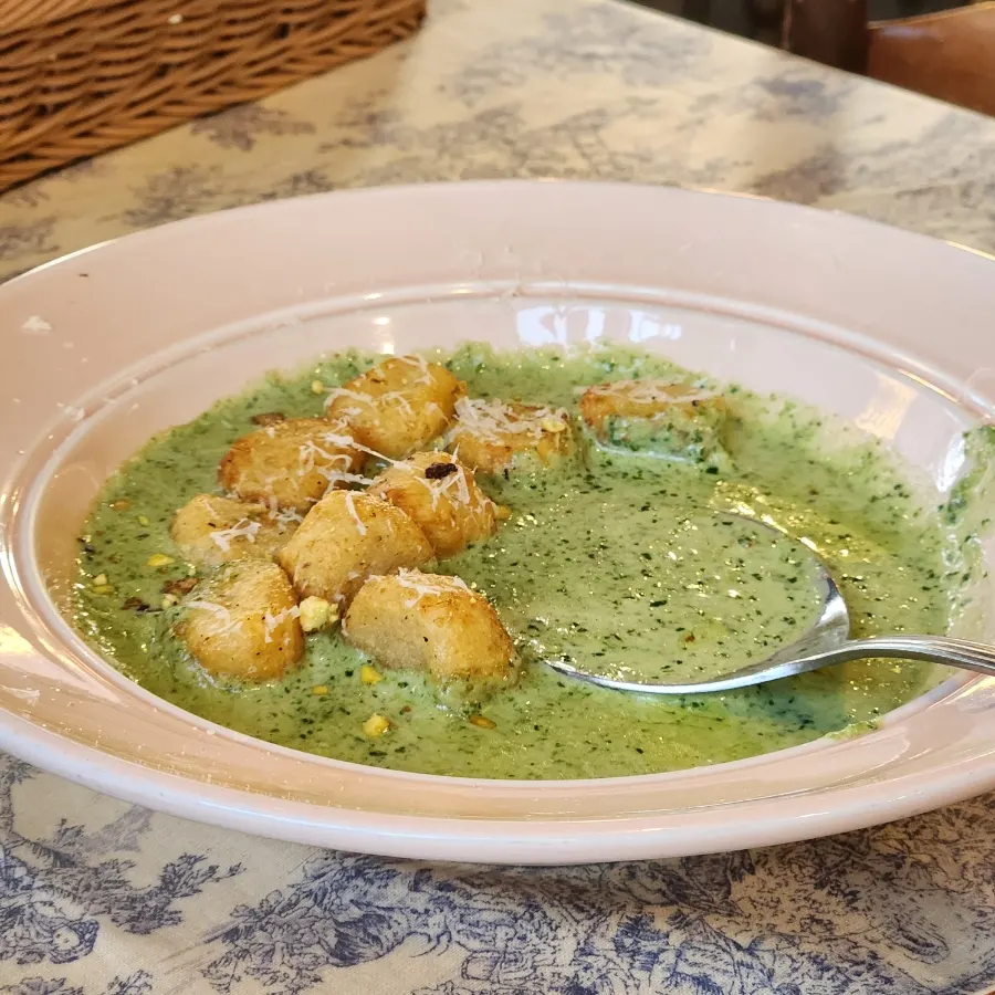 Close-up of gnocchi coated in basil cream sauce
