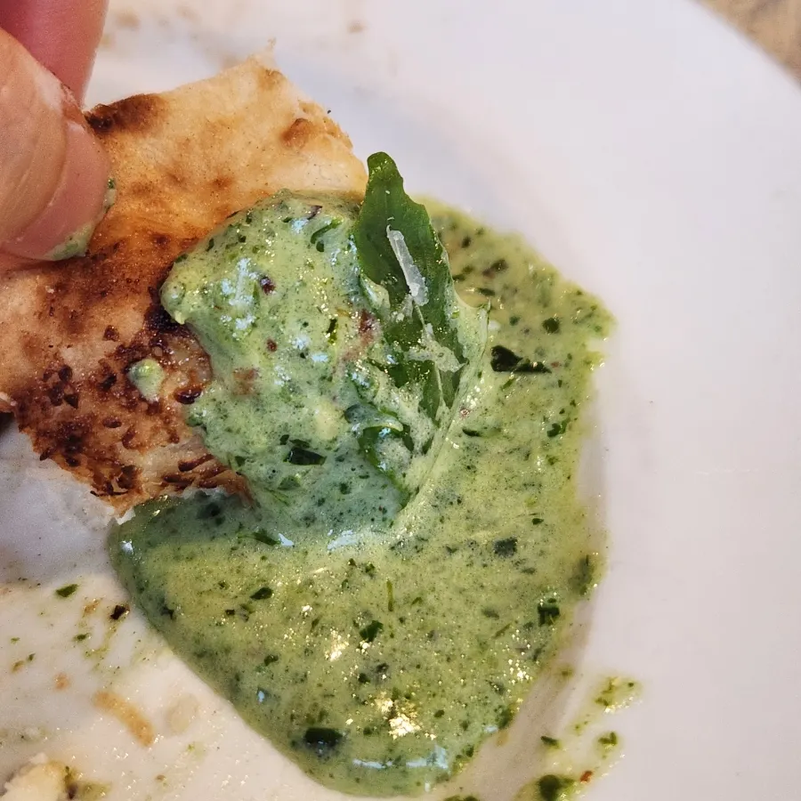 Scooping up basil cream sauce with wood-fired bread