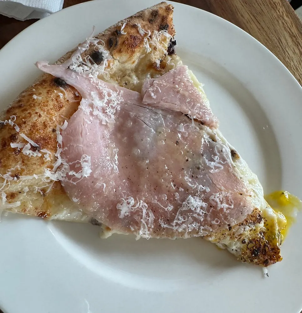Slice of Bismarck pizza with egg yolk running out