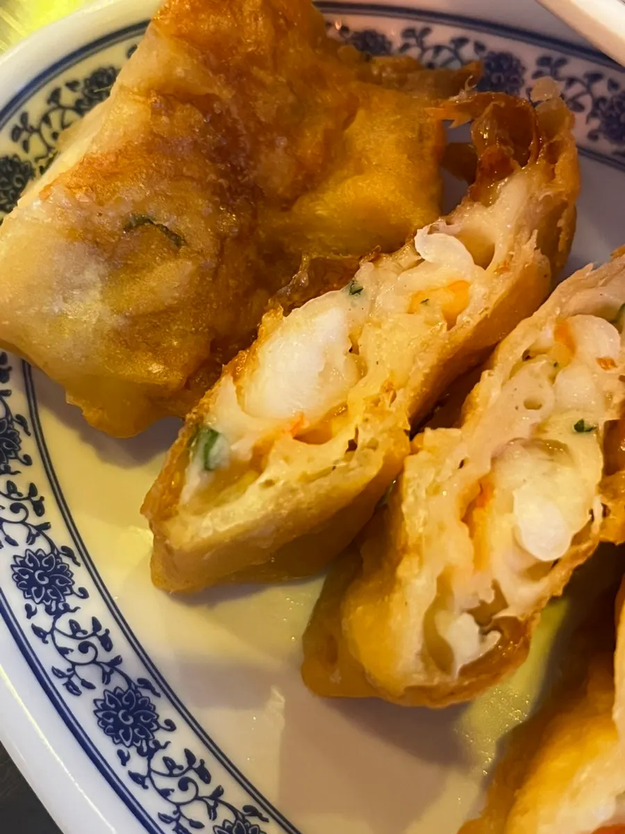 Cross-section of a fried shrimp roll dipped in sauce