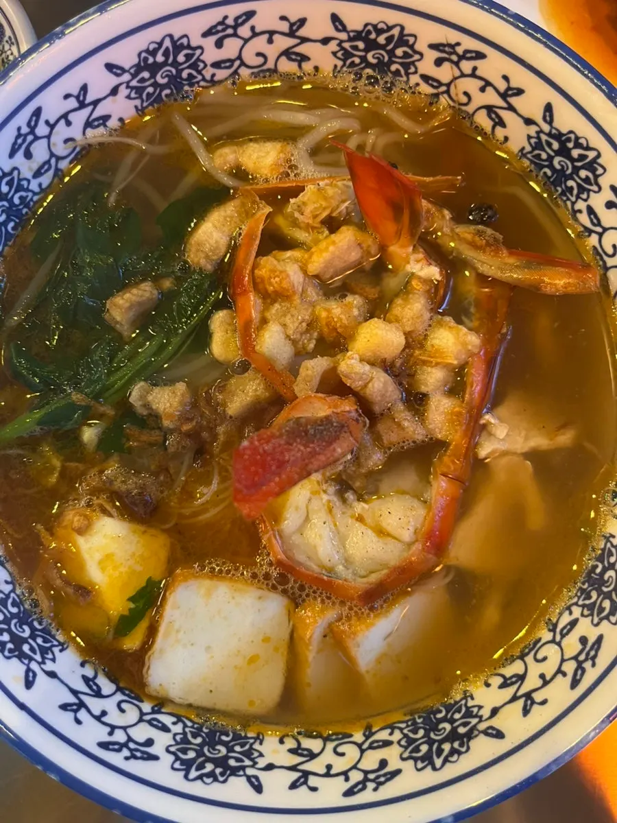 A bowl of shrimp noodles topped with jumbo prawn