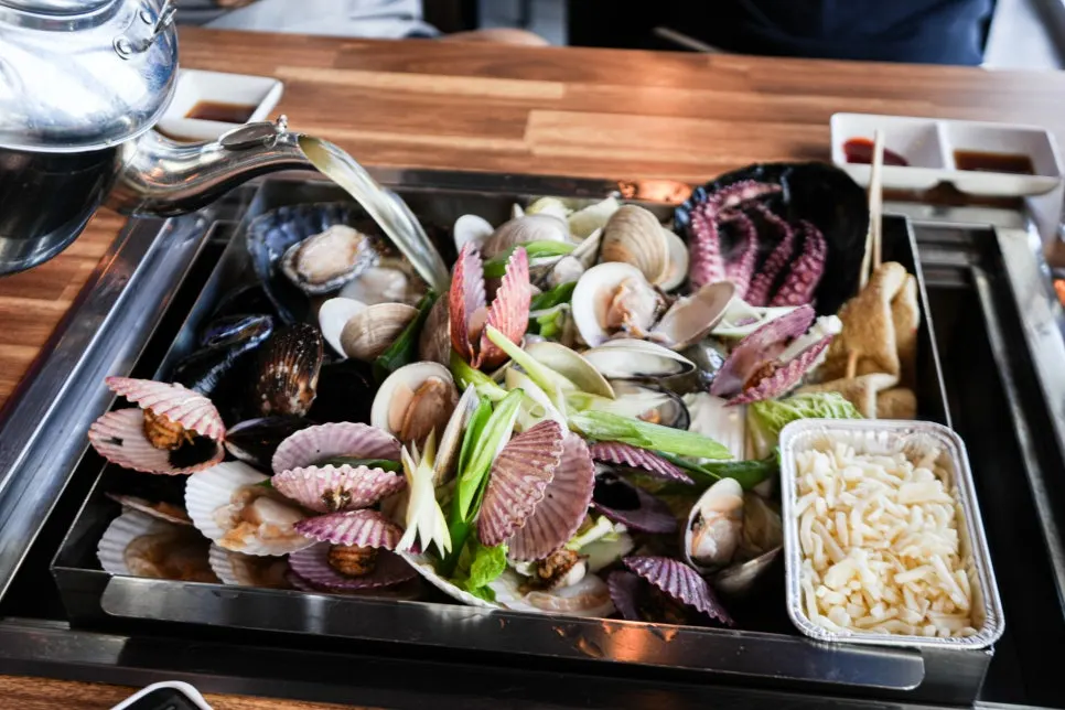 Pot of broth steamed clams piled with blue crab and seafood