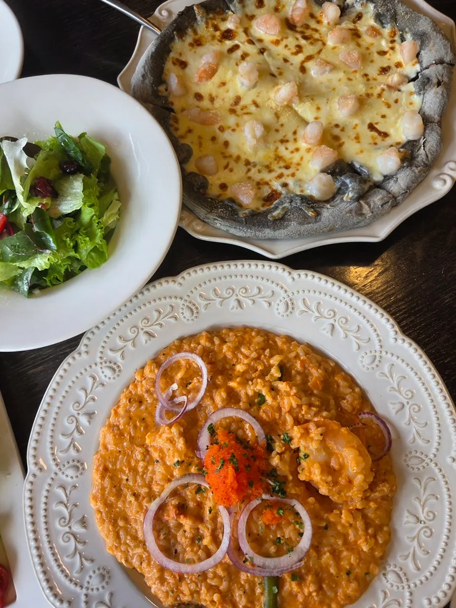 Table spread with basic salad, pizza, and risotto together