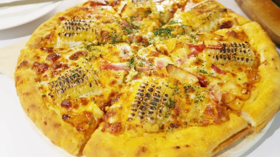 Top of the pizza covered in cheese and corn kernels