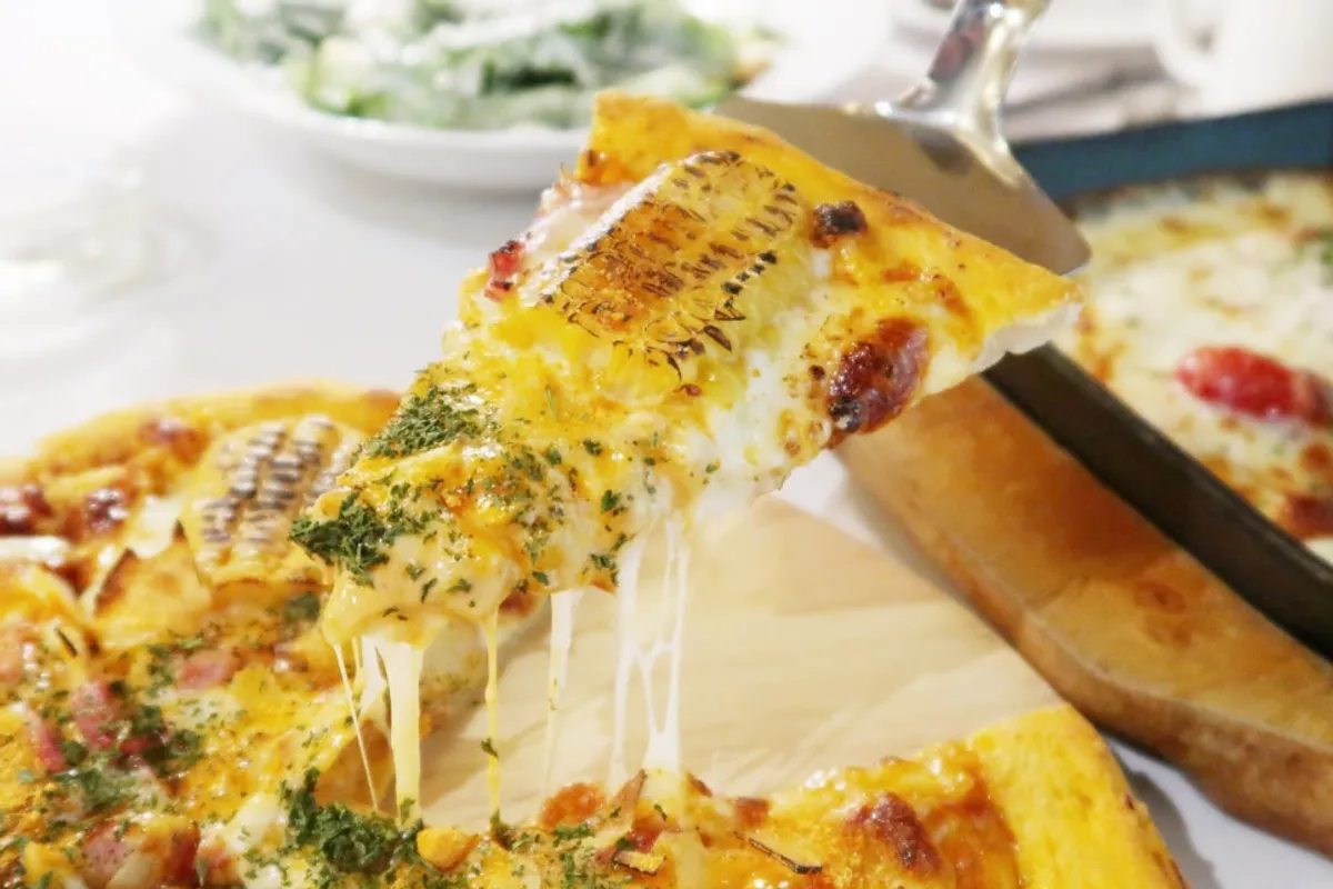Cheese stretching long as a slice of corn pizza is lifted