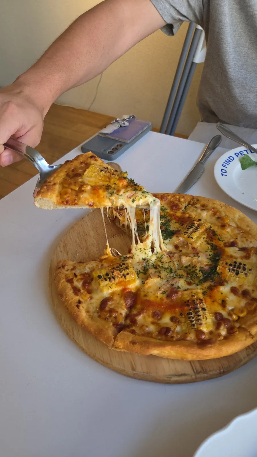 A slice of corn pizza with stretchy cheese