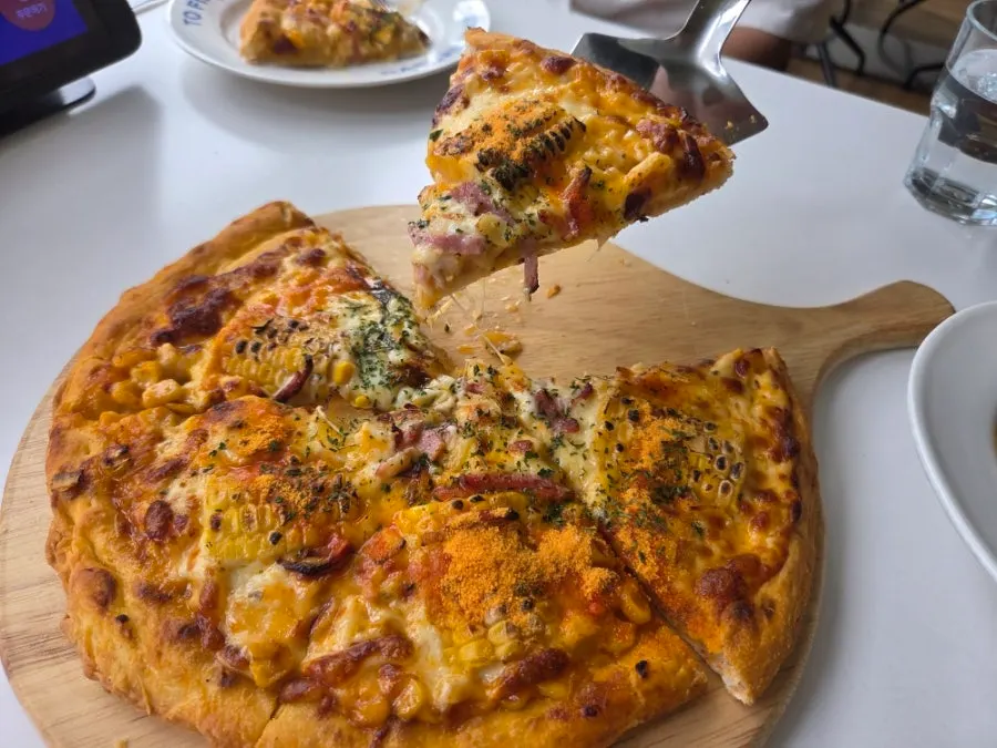 A slice of corn pizza with chewy dough