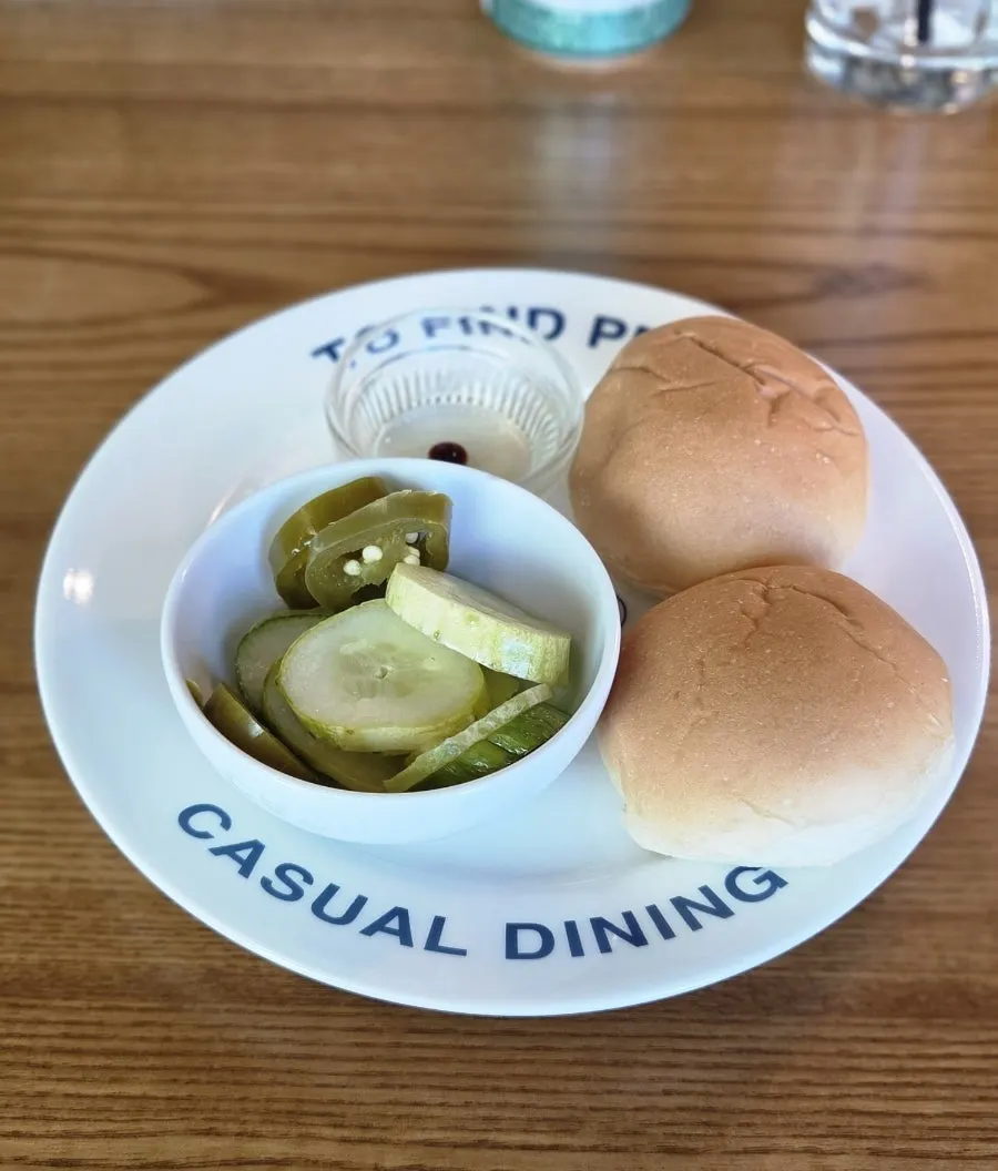 Two dinner rolls and pickles served before the meal