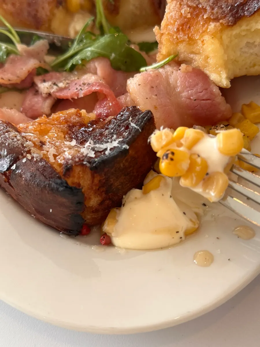 A piece of toast topped with corn mayo and bacon
