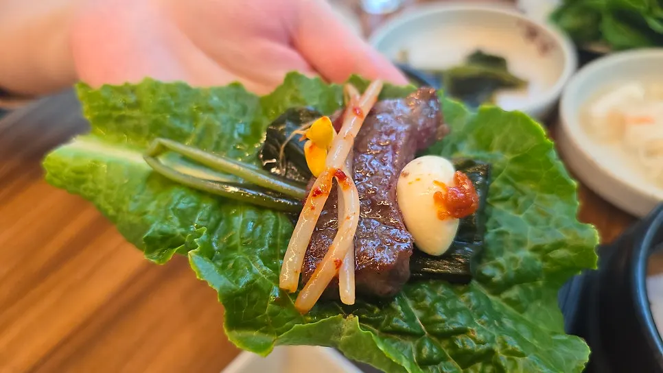 A rib wrap with myeongi namul and garlic on top