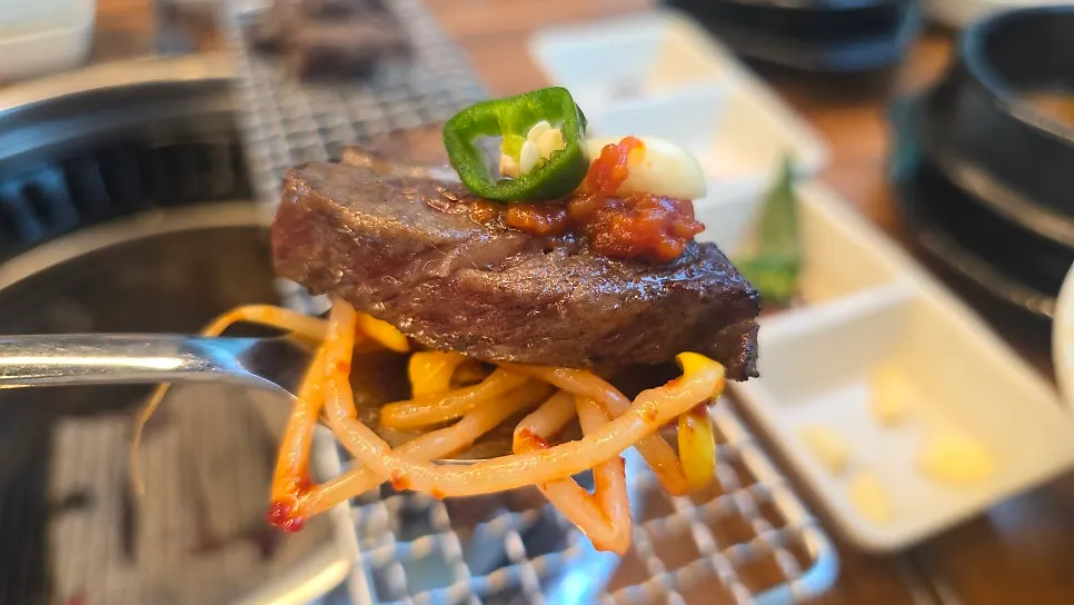 A piece of meat topped with bean sprouts and cheongyang chili