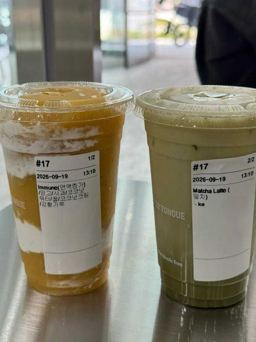 A layered yellow smoothie next to a green matcha latte