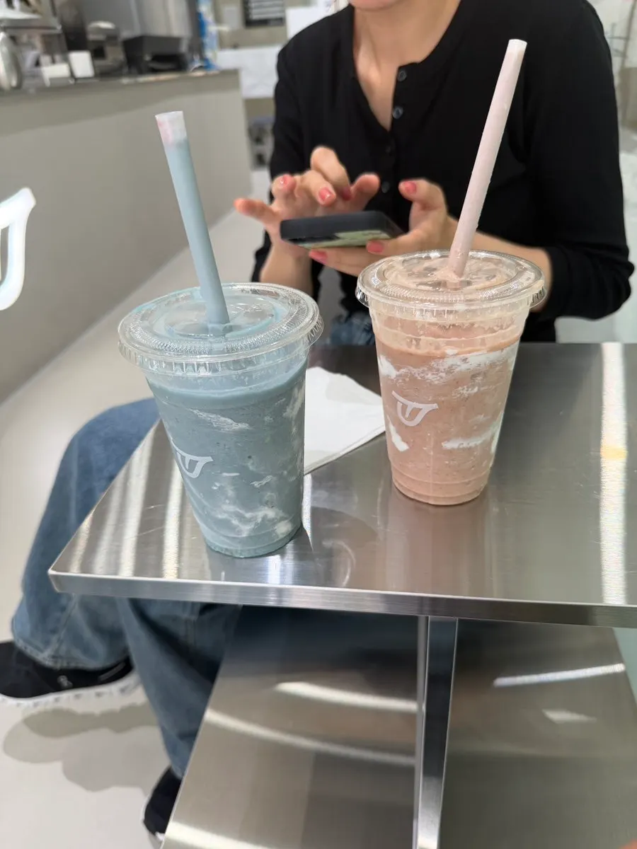 Two smoothies on a small table with companion behind