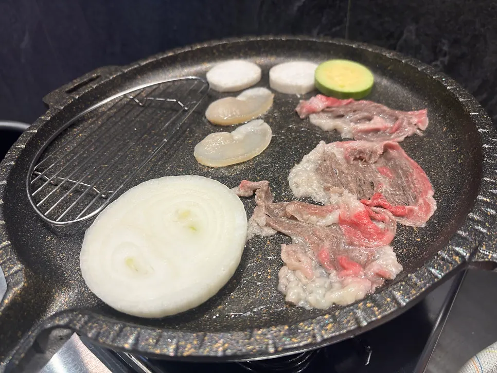 Brisket and aged kimchi cooking on the grill plate