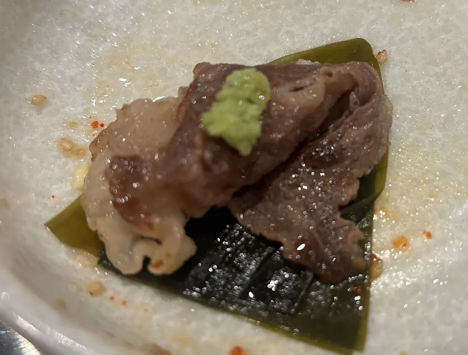 A samhap bite with brisket topped with scallop and aged kimchi