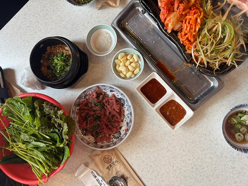 Satu set banchan melimpah lengkap dengan yukhoe dan sayuran bungkus