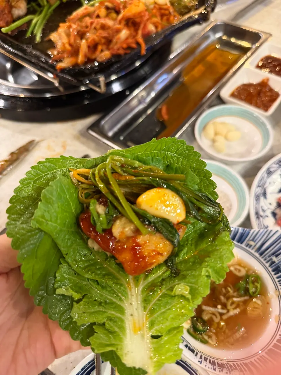 Pork belly wrap topped with minari and kimchi