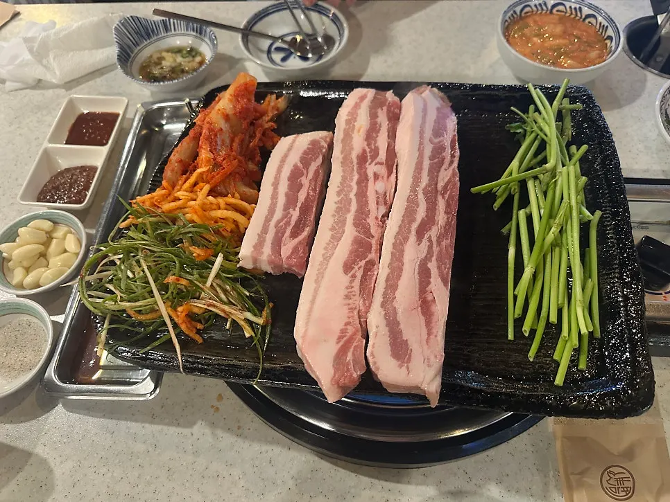 Three servings of pork belly placed on the grill at once