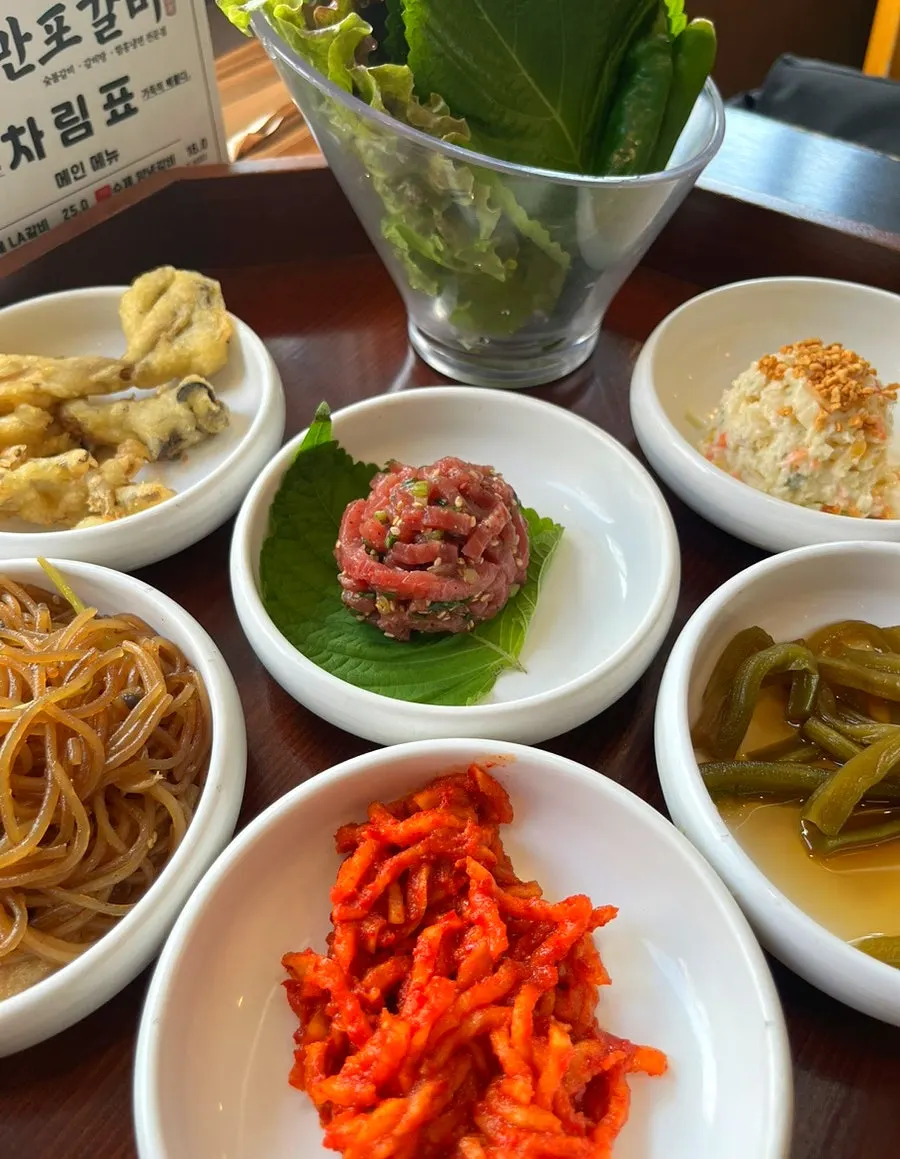 Generous basic side dishes including fried mushrooms, japchae, and potato salad