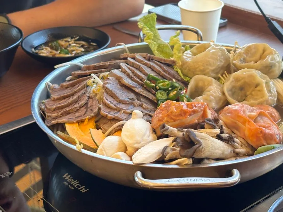 끓고 있는 만두전골 국물과 버섯, 채소
