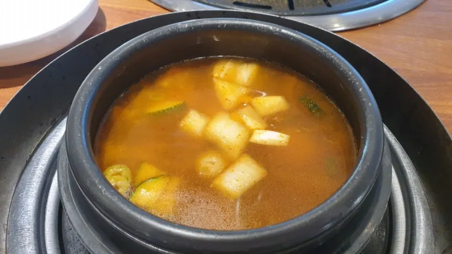Doenjang jjigae simmering on its dedicated burner beside the grill