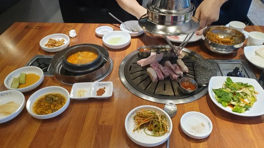 Table spread with doenjang jjigae and a bowl of rice alongside the meat
