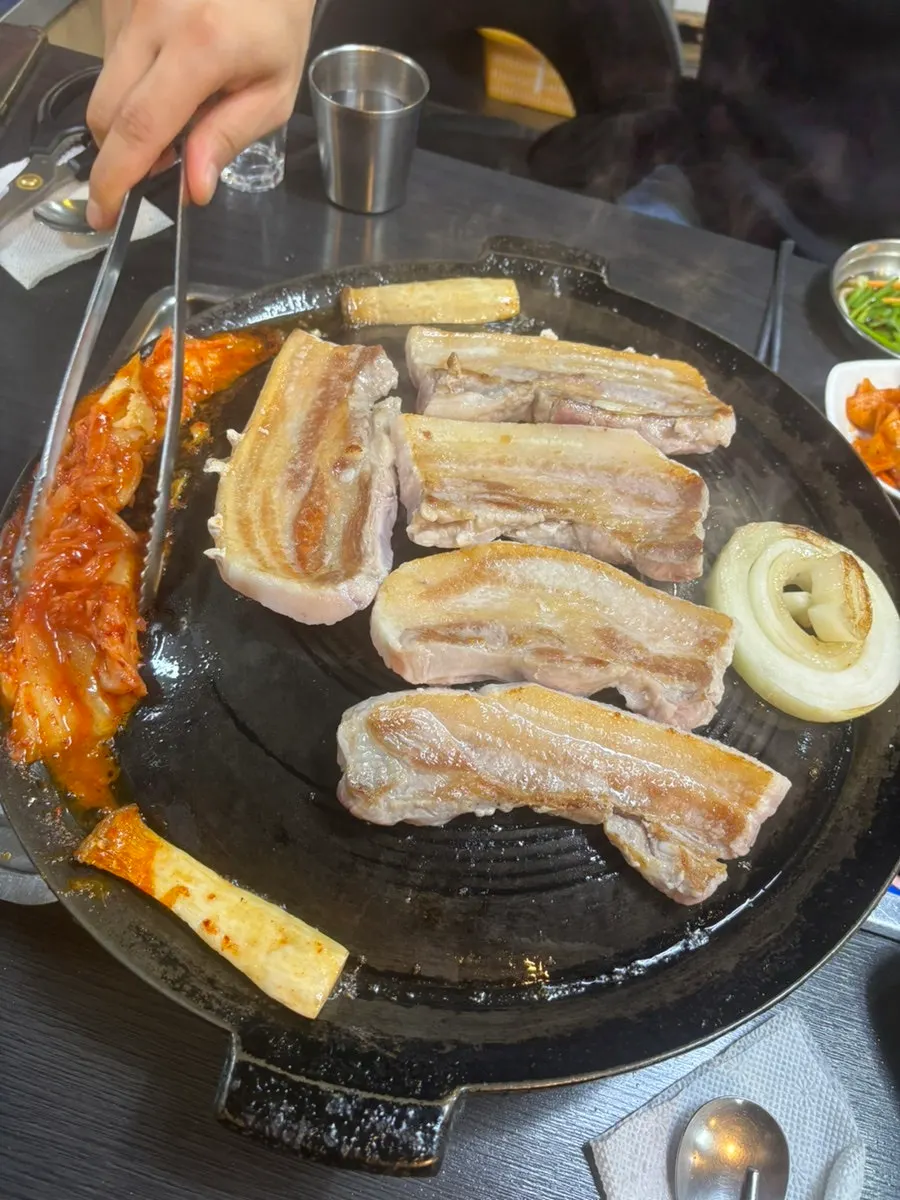 Pork belly and kimchi cooking on the grill