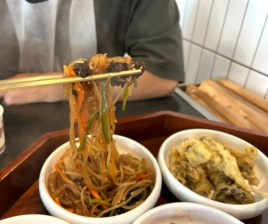 Steaming warm japchae and wrap greens