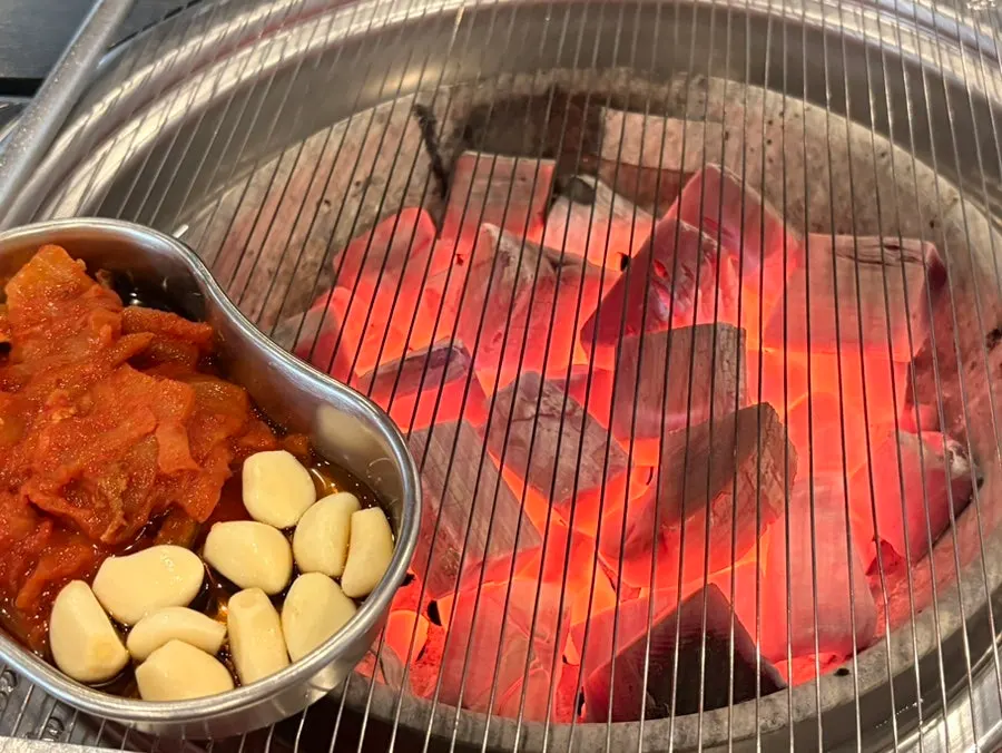 Charcoal, kimchi, and garlic brought to the middle of the table