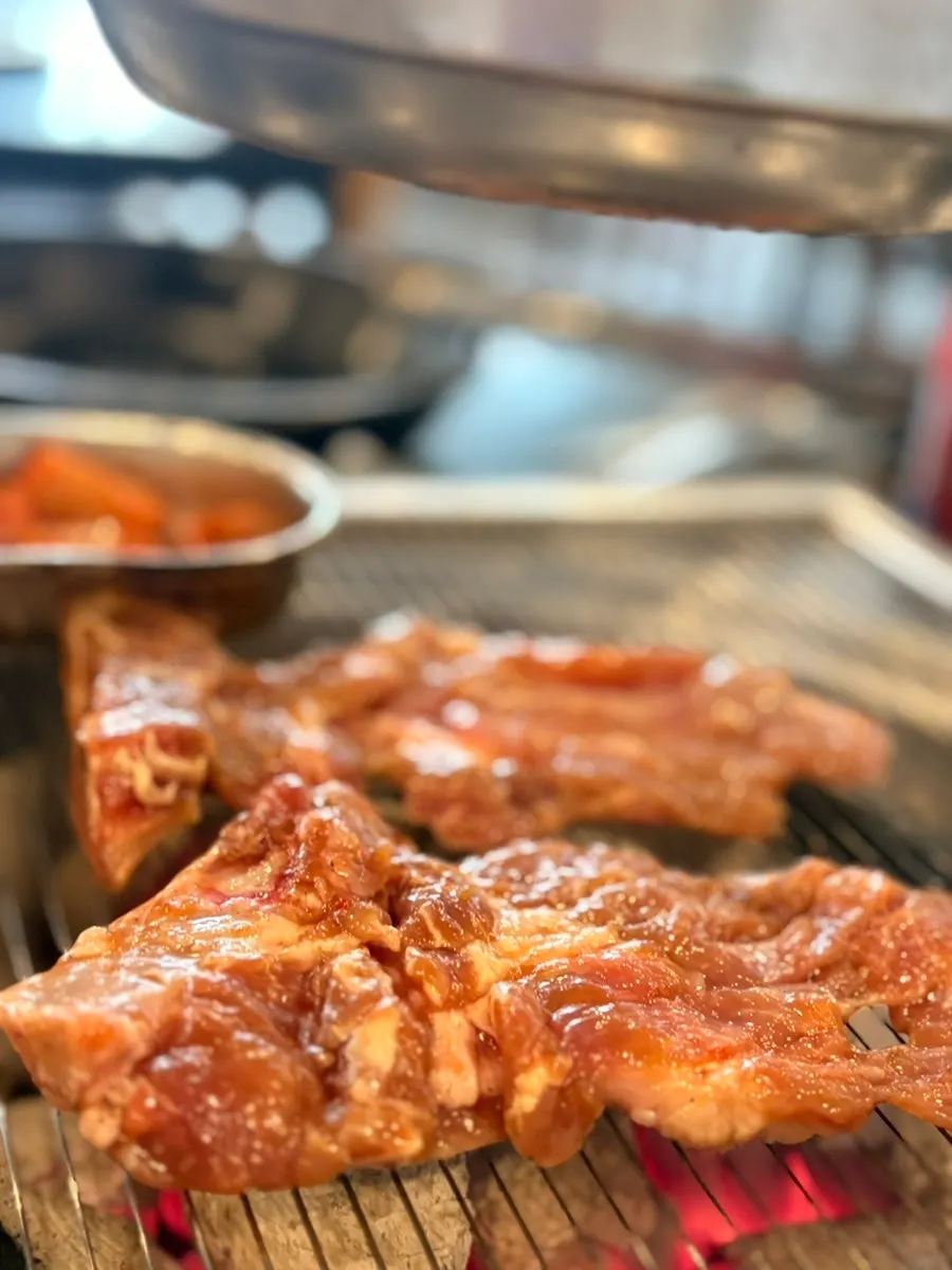 Marinated galbi being flipped on the grill rack