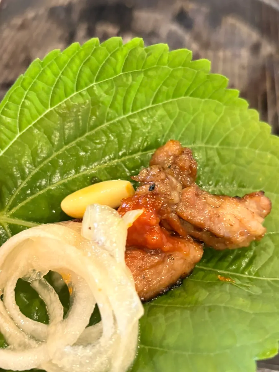 A perilla leaf ssam with meat, onion, garlic, and kimchi