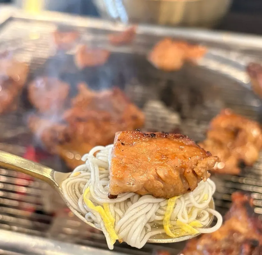 A piece of charcoal galbi placed on top of water naengmyeon