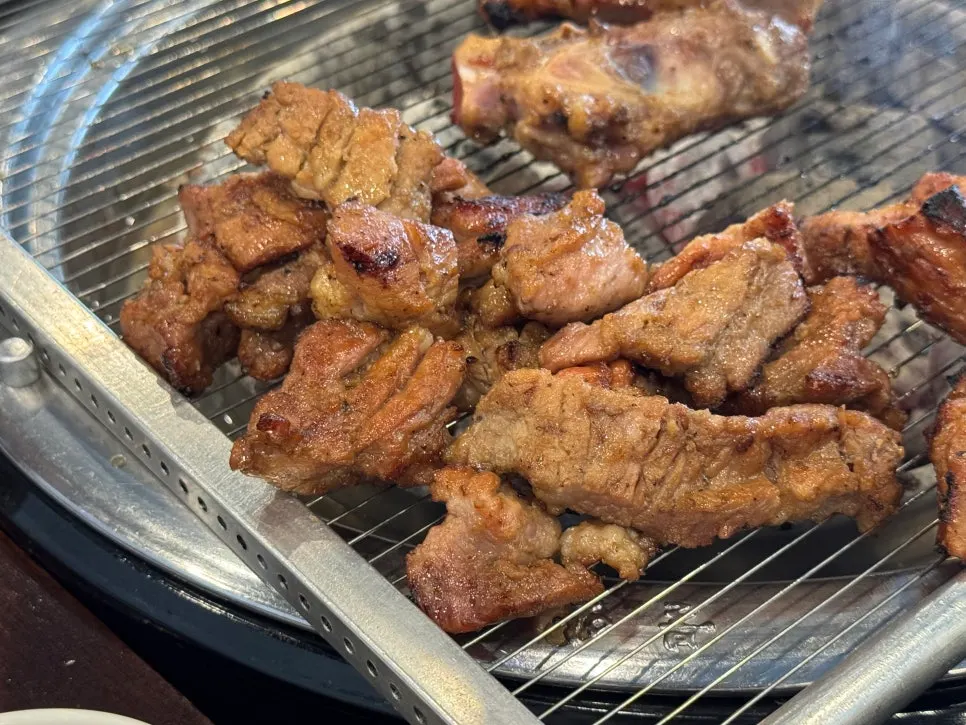Table with pork galbi over charcoal and side dishes