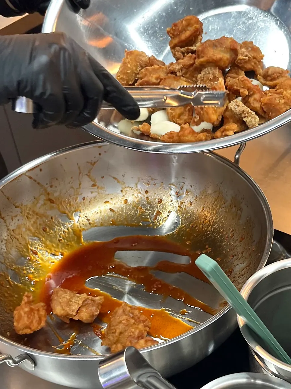 Pouring sauce over chicken and rice cake and tossing