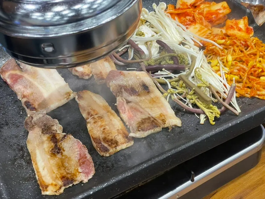 Thin-sliced pork belly grilling on the tabletop grill