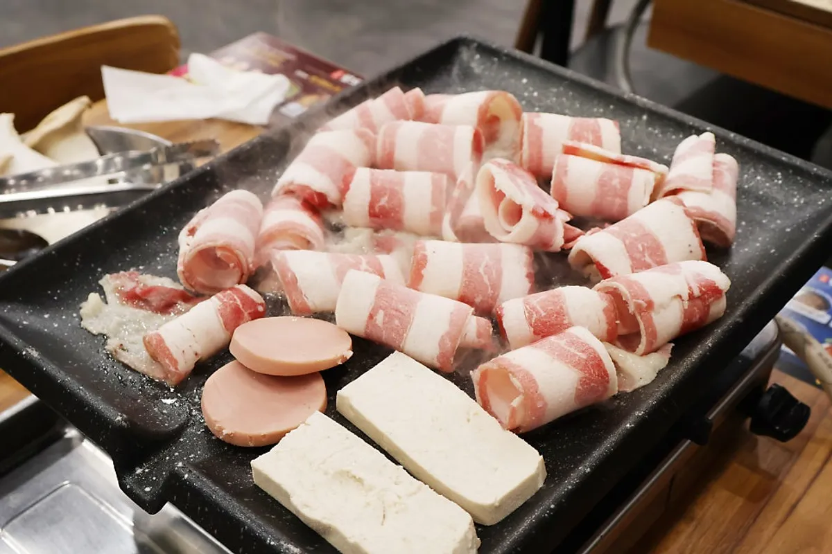 Thin-sliced pork belly cooking on the grill